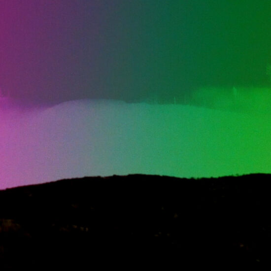 Silhouette of hills with sky above in a gradient from purple to green