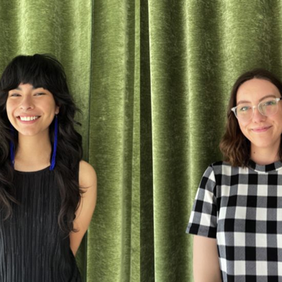 Photo of two smiling women in front of a green velvet curtain