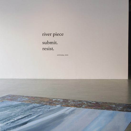 A light pink wall featuring large font text reads “river piece, submit. Resist”. On the ground in front of the wall there is a printed image of wild cranberries pasted onto the floor, and a large piece of printed nylon above it, displaying the image of a river.
