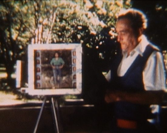 Man showing photograph of woman on vintage camera
