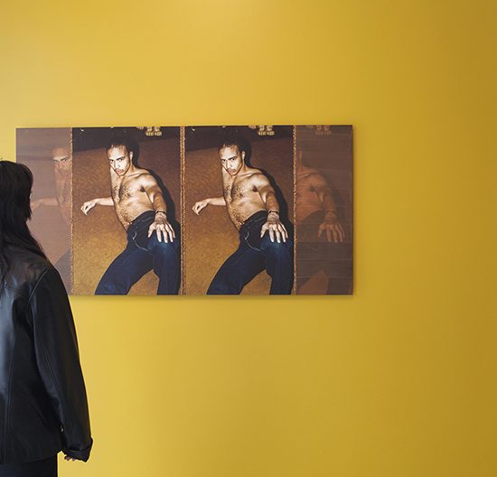 Woman stands in front of diptych hanging on a yellow wall