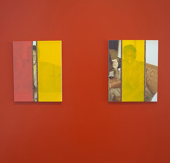 2 photographs hang on a red wall, they have large red and yellow colour blocks obscuring the subjects of the photographs
