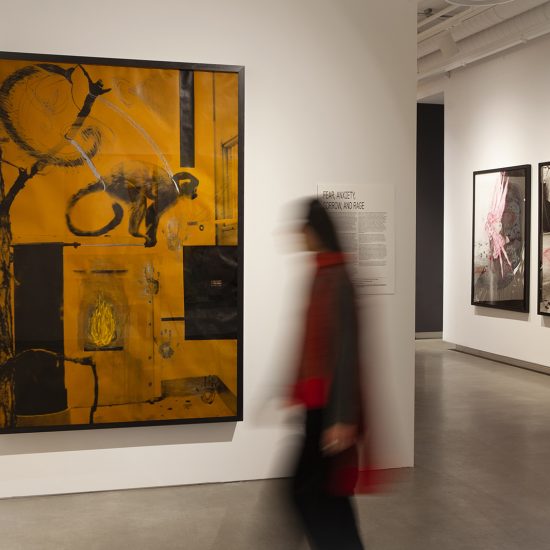 A figure moves in front of a large scale collage