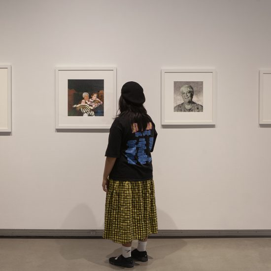 woman stands in front of a gallery wall with her back to us. She's engaging with four pictures on the wall, hung in line.