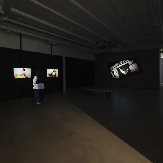 Video installation in gallery two taken from lobby entrance. Two tv installations are hung to the left, showed in colour. A large, wall sized projection in black and white is cast onto the back wall.